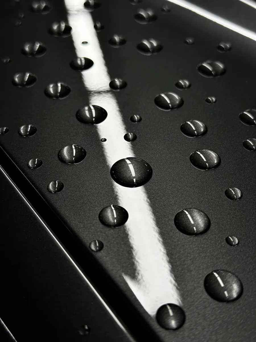 Water beading tightly across freshly polished dark paintwork.